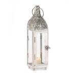 Highly polished metal highlights the intricately carved top of this stunning candle lantern. With four glass panels, a large top ring for hanging, and a fascinating door latch, this lighting accent will draw the gaze of many admirers