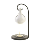 With a generous dollop of charm, this striking oil warmer will mesmerize you with its simple elegance. A metal loop balances the ceramic oil basin above a seated tealight to give off a warm glow and delicate scent. 